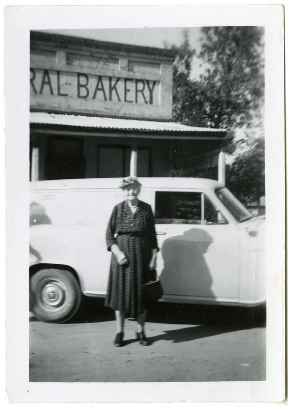 Lil Dunstan in front of the Federal Bakery with the Bakery's Holden panel van behind, 1955. ARM 14.075