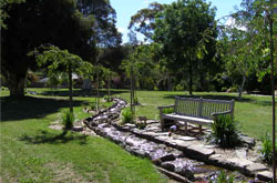 a seat next to the watercourse at Glenmorus Gardens